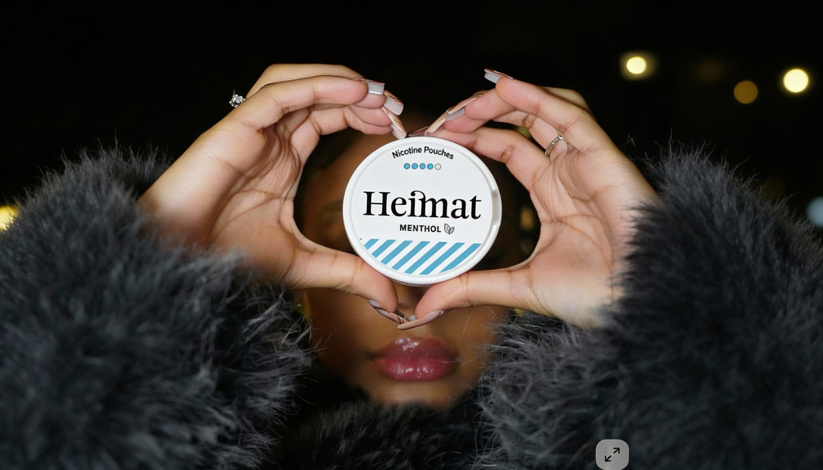 Heimat Menthol σακουλάκια νικοτίνης σε δοχείο σε σχήμα καρδιάς που κρατά μια γυναίκα με μαύρο παλτό, φωτογραφία lifestyle